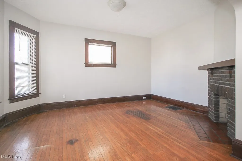 Unfurnished living room with wood-type flooring, plenty of natural light, and a fireplace