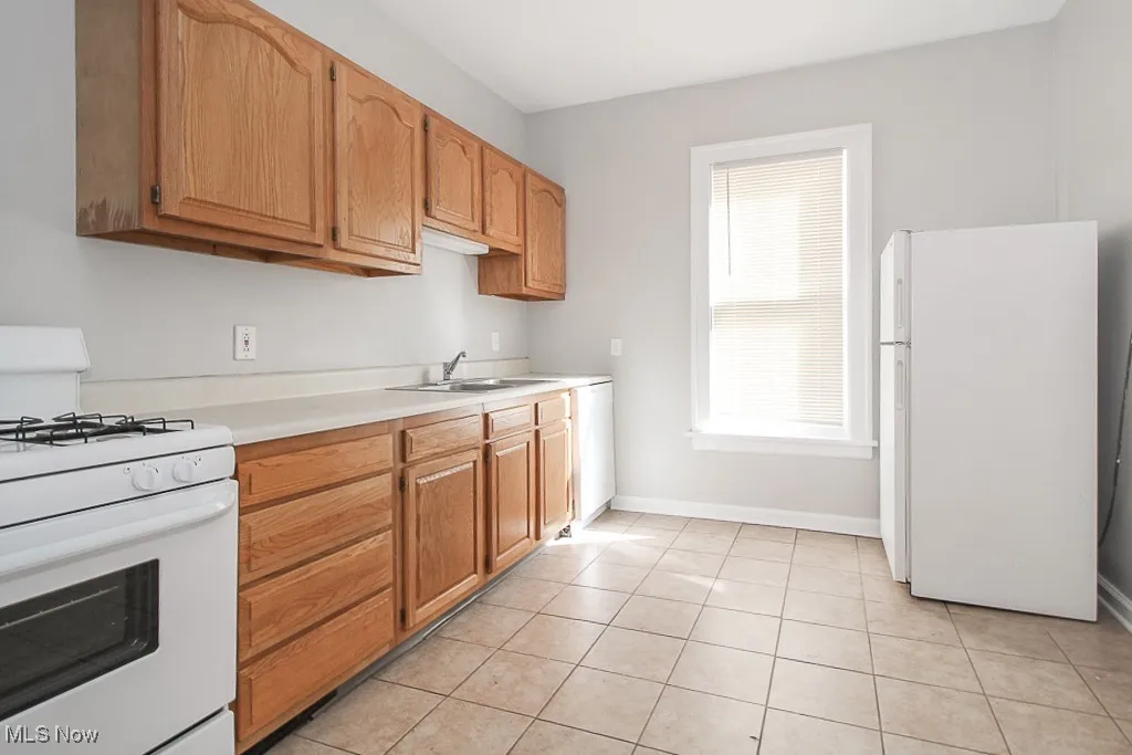 Kitchen featuring white appliances, light countertops, and light tile patterned flooring
