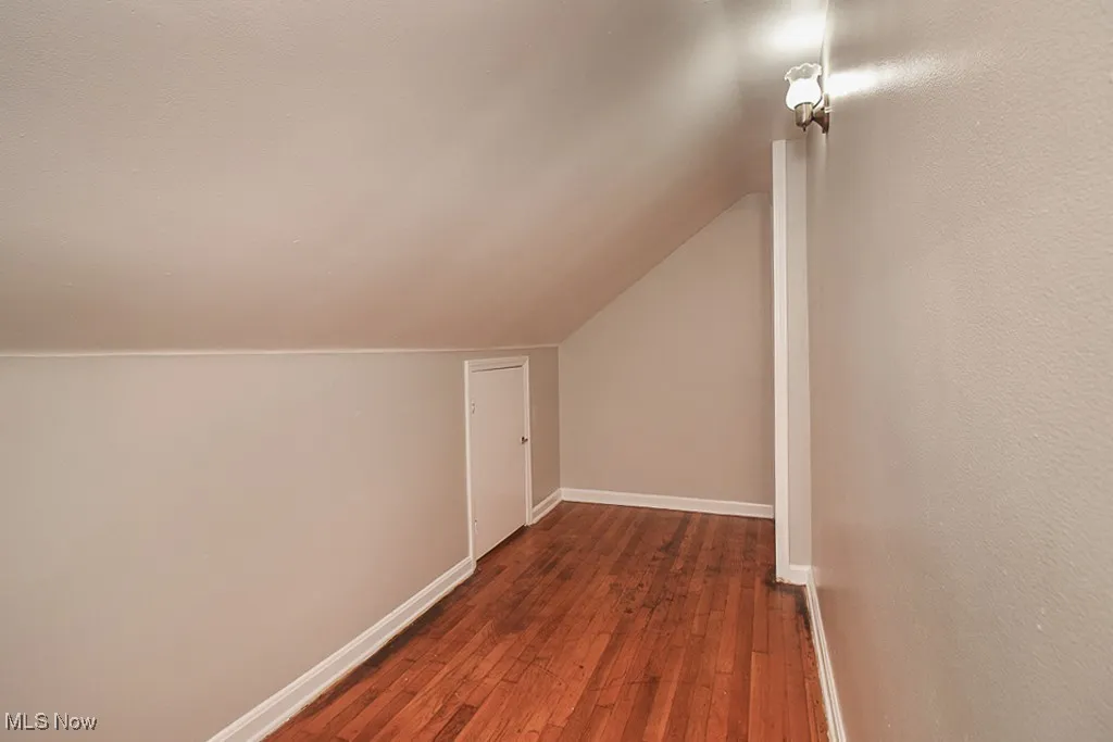 Additional living space featuring dark wood-style flooring and lofted ceiling