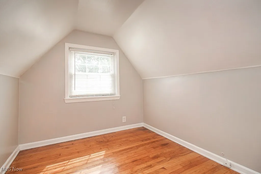 Additional living space with light wood finished floors and vaulted ceiling