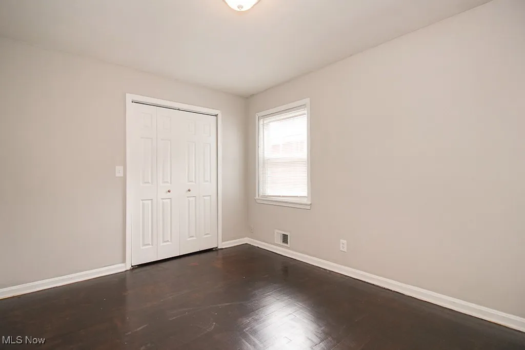 Unfurnished bedroom with a closet and dark wood-style floors