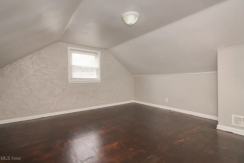 Additional living space with wood finished floors and lofted ceiling