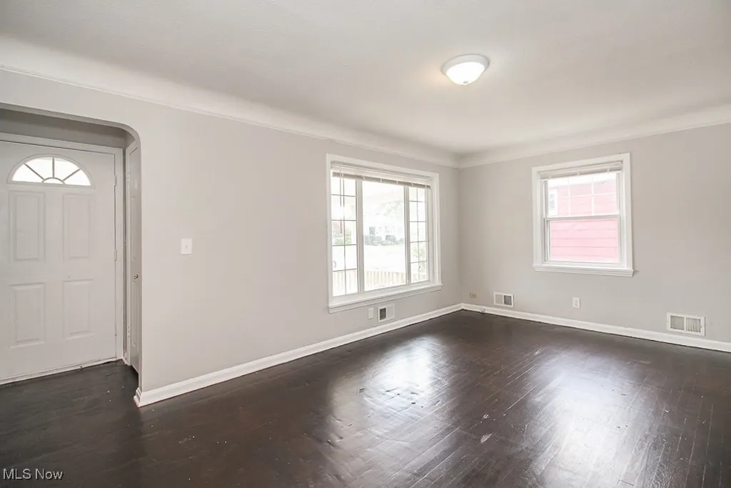 Entryway with dark wood-type flooring, ornamental molding, and arched walkways
