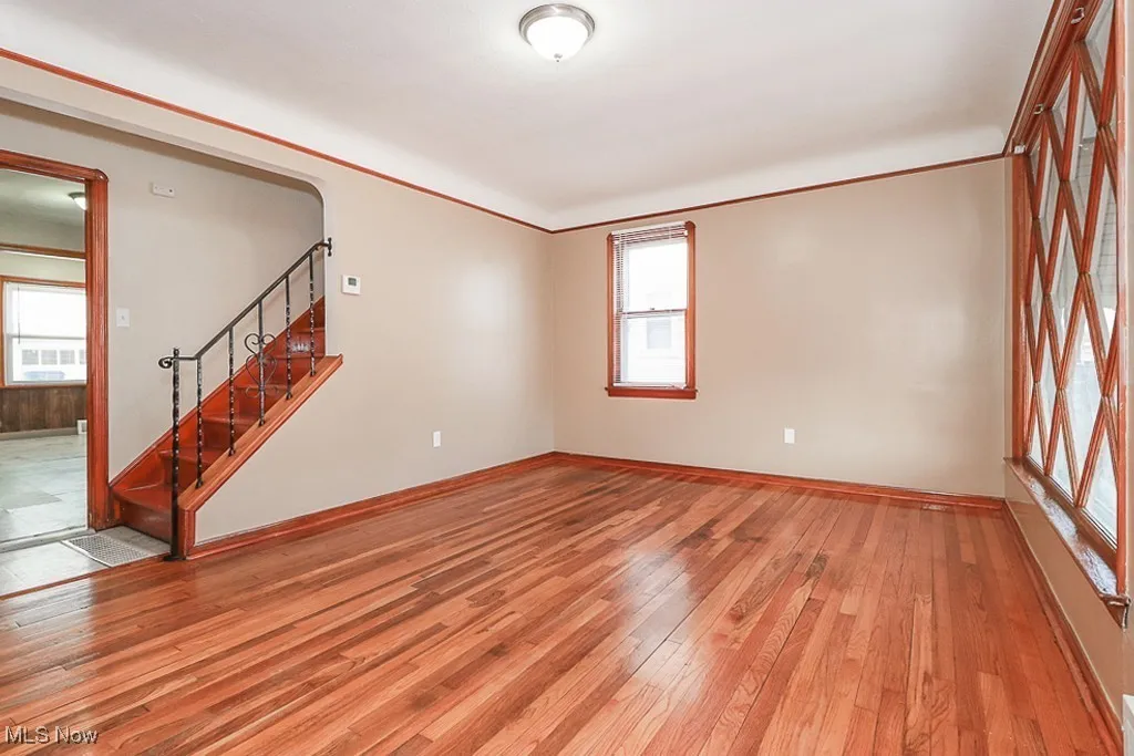 Spare room featuring wood-type flooring, stairs, and crown molding