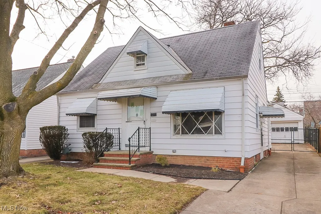 View of front of house with roof with shingles, an outdoor structure, a garage, and a chimney