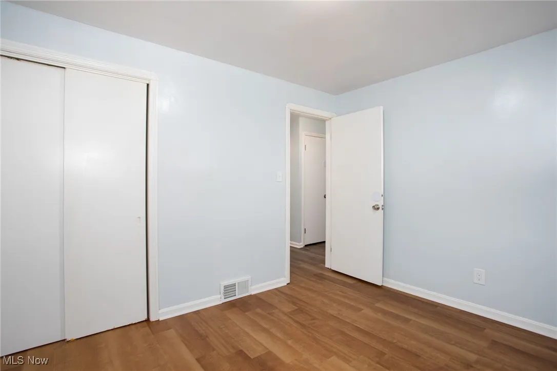 Unfurnished bedroom with wood finished floors and a closet