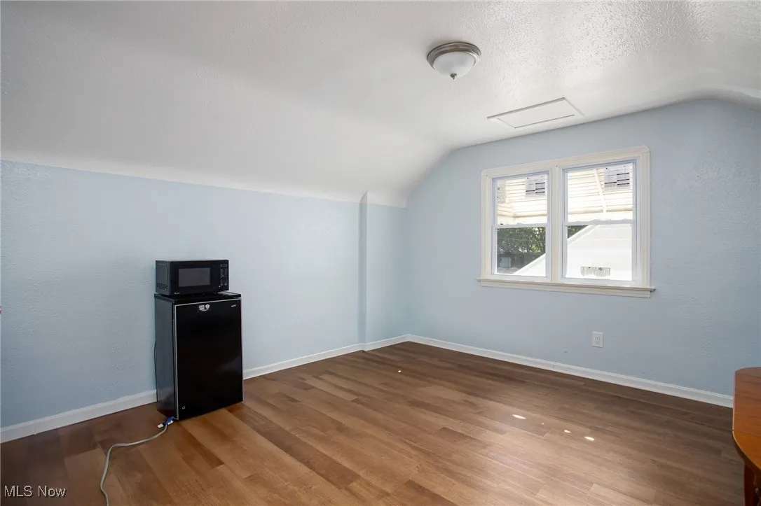 Bonus room with vaulted ceiling, wood finished floors, and a textured ceiling