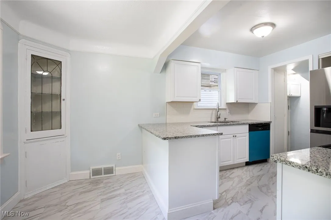 Kitchen with dishwasher, light marble finish flooring, white cabinets, and light stone countertops