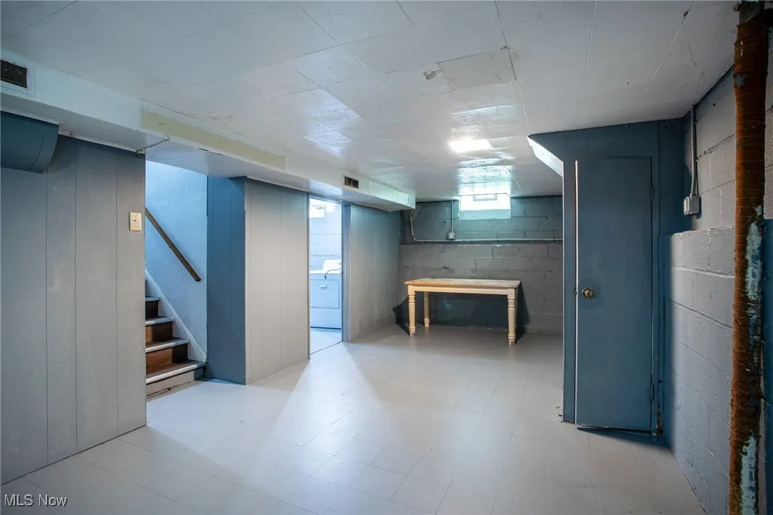 Basement with stairs, light floors, and washer / clothes dryer