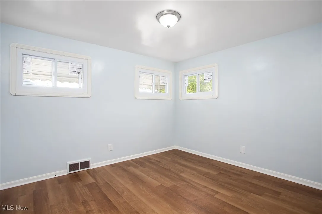Empty room with baseboards and dark wood-style flooring