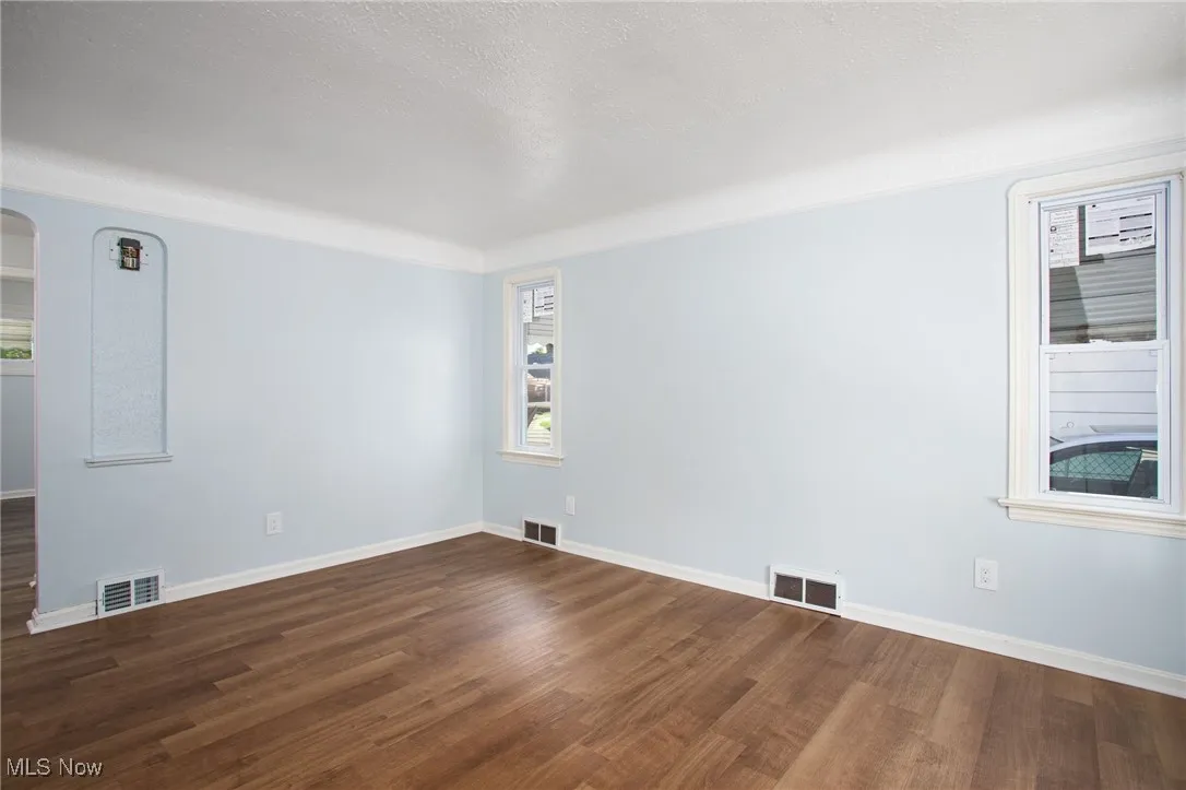 Spare room featuring dark wood-style flooring and arched walkways