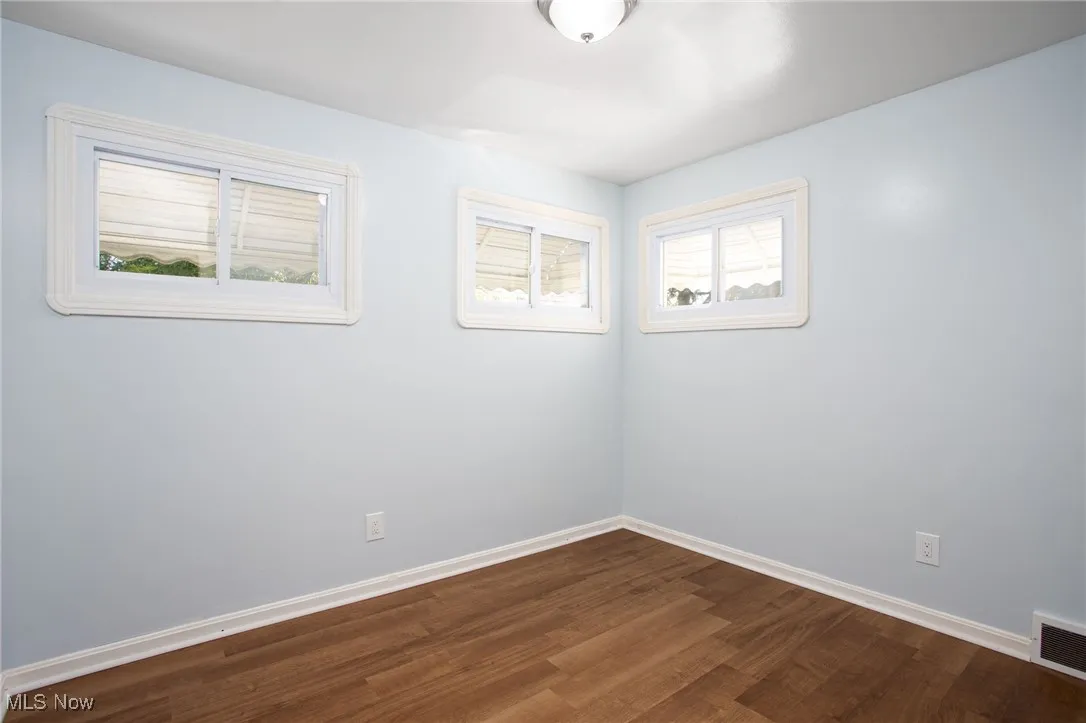 Empty room with dark wood finished floors and baseboards