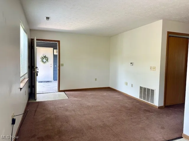 Carpeted spare room featuring a textured ceiling