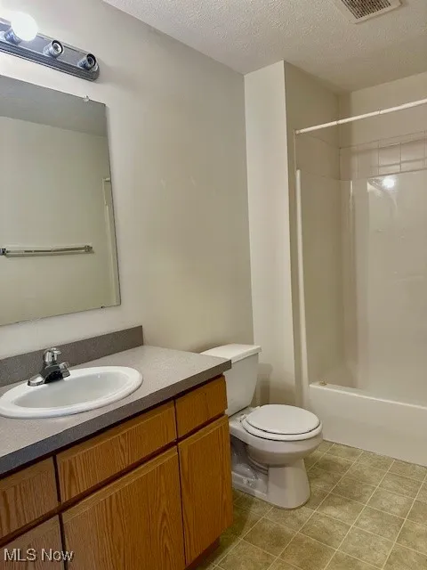 Bathroom with vanity, shower / bath combination, and a textured ceiling