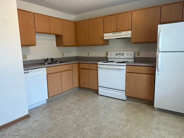 Kitchen with freestanding refrigerator, range, extractor fan, dishwashing machine, and a textured ceiling
