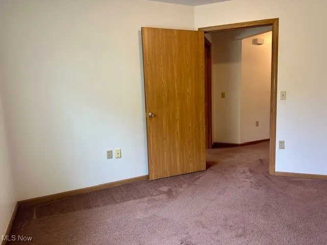 Carpeted empty room featuring baseboards