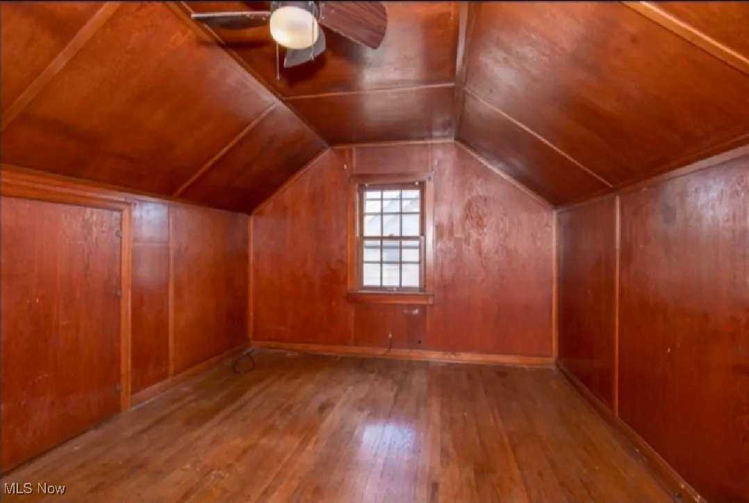Additional living space featuring hardwood / wood-style floors, ceiling fan, lofted ceiling, wooden ceiling, and wooden walls