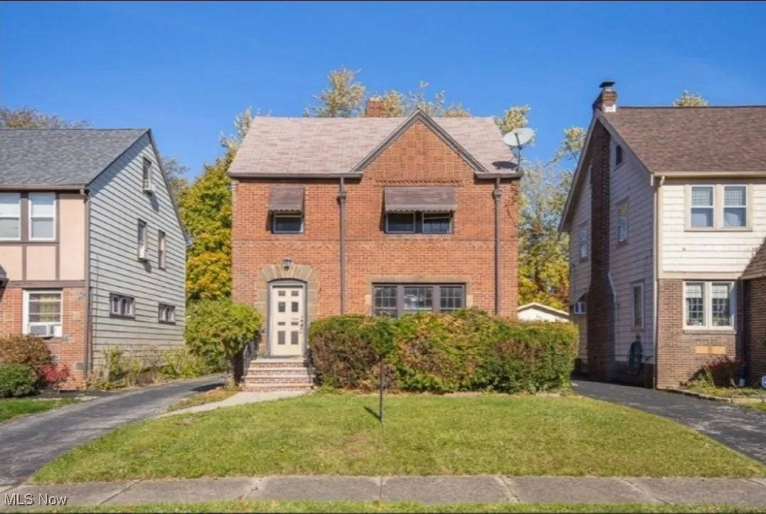 Tudor-style house featuring brick siding and a front lawn