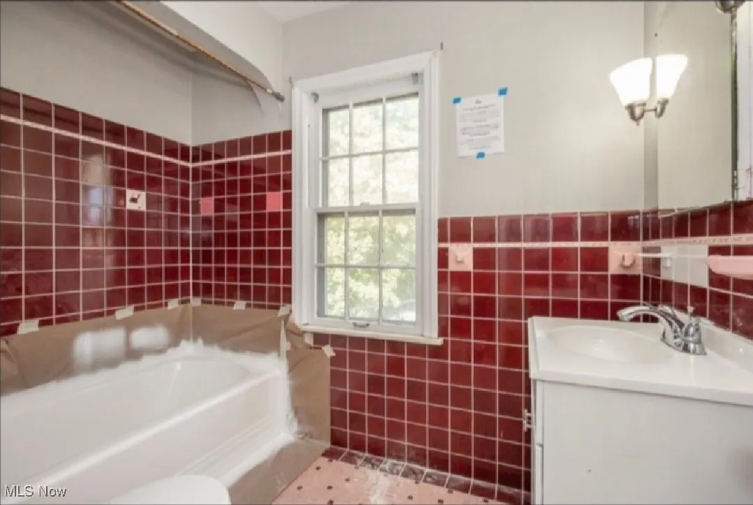 Bathroom with tile walls, a garden tub, vanity, and plenty of natural light