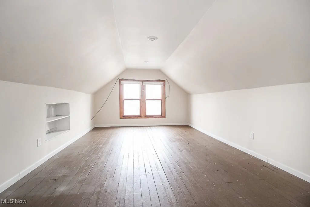 Bonus room featuring built in features, hardwood / wood-style flooring, and vaulted ceiling