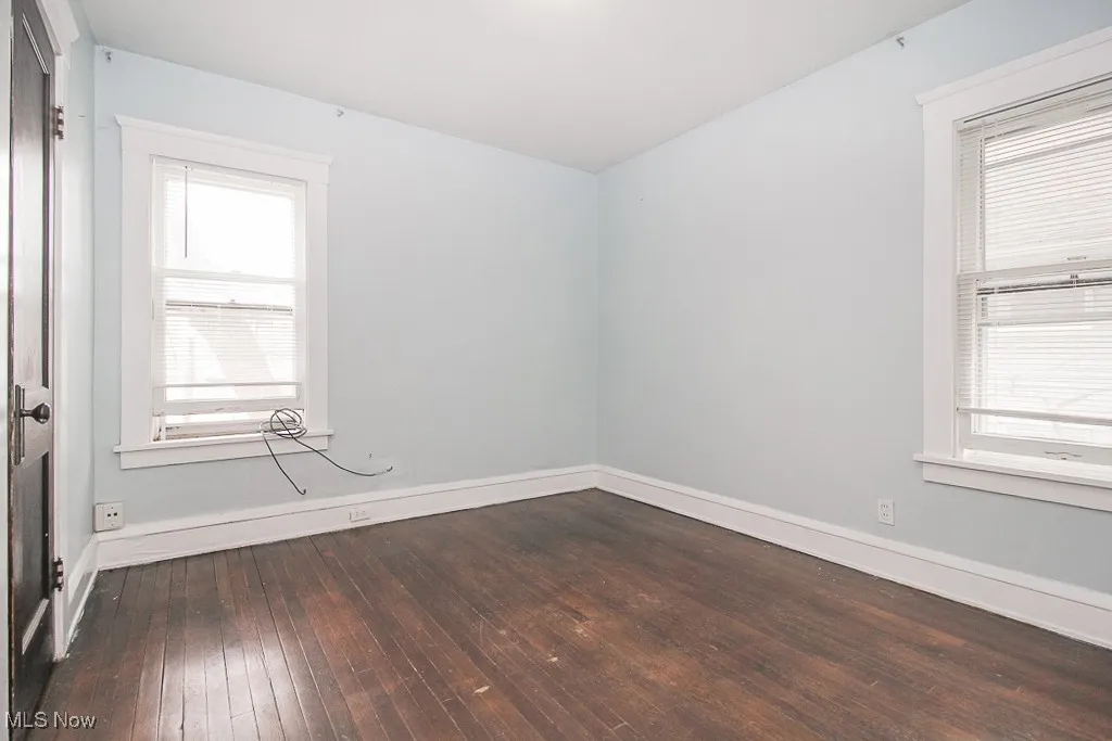 Unfurnished room featuring dark wood-style floors and baseboards