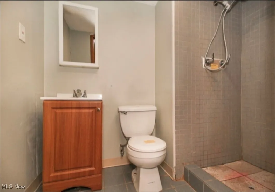 Full bath featuring a tile shower, vanity, and tile patterned flooring