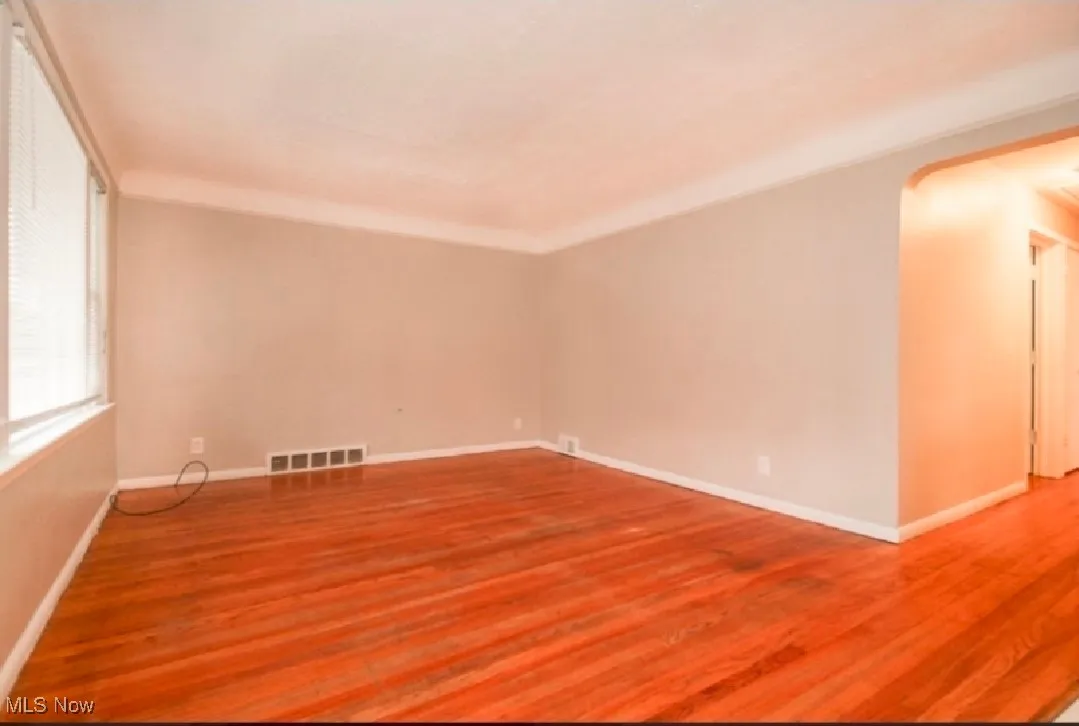 Empty room featuring wood finished floors and arched walkways