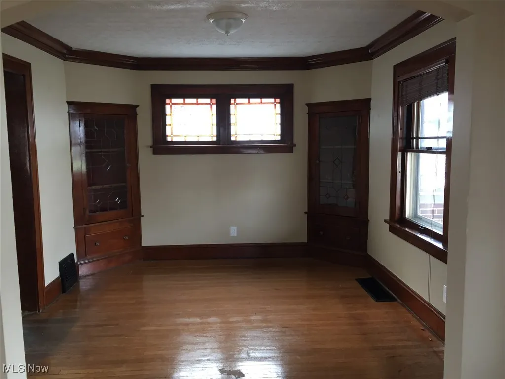 Unfurnished room with ornamental molding, plenty of natural light, and hardwood / wood-style floors