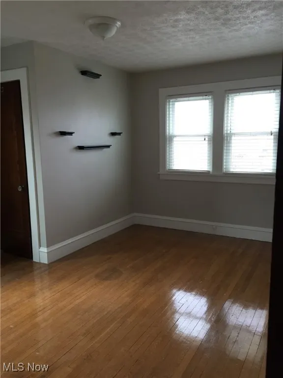 Spare room featuring hardwood / wood-style floors and a textured ceiling