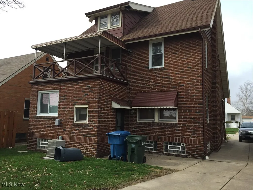 Back of house with a balcony, brick siding, and a shingled roof
