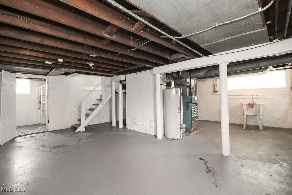 Below grade area featuring water heater and stairway