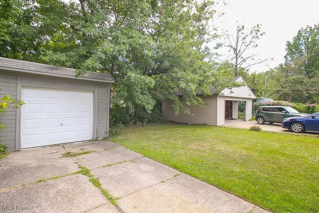 View of grassy yard featuring an outbuilding, driveway, and a garage