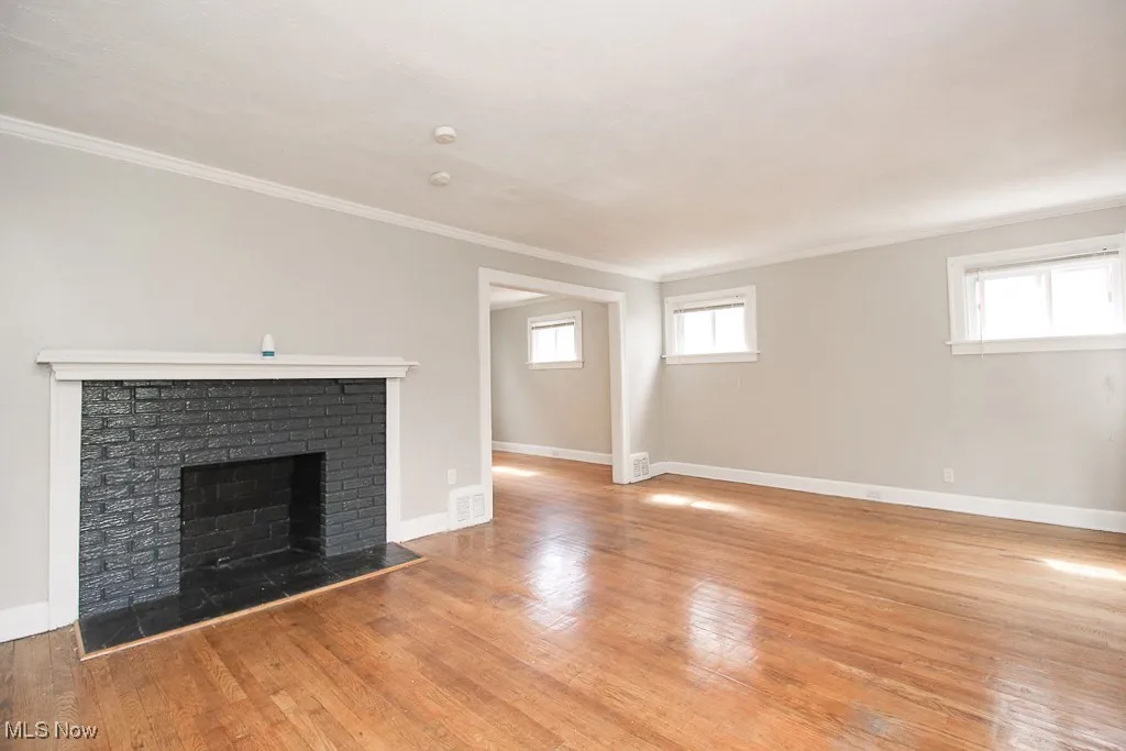 Unfurnished living room with ornamental molding, a fireplace, and wood finished floors