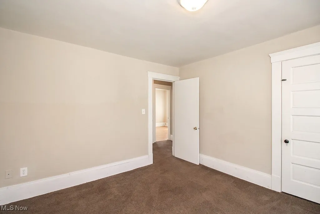 Unfurnished room with dark colored carpet and baseboards