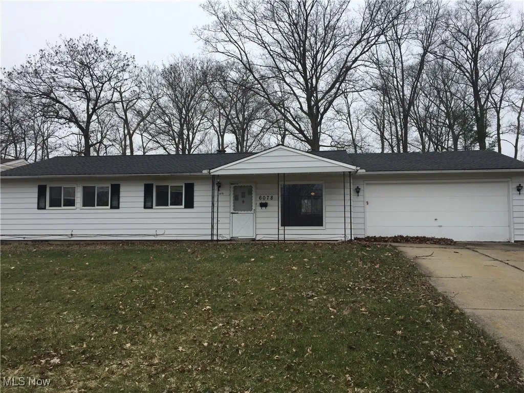 View of front of house with concrete driveway, an attached garage, and a front lawn