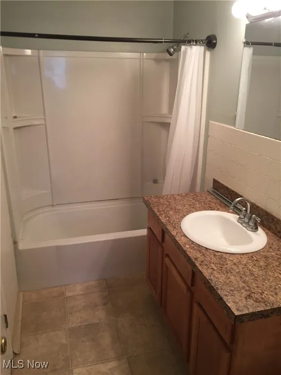 Full bathroom featuring shower / bathtub combination with curtain and vanity