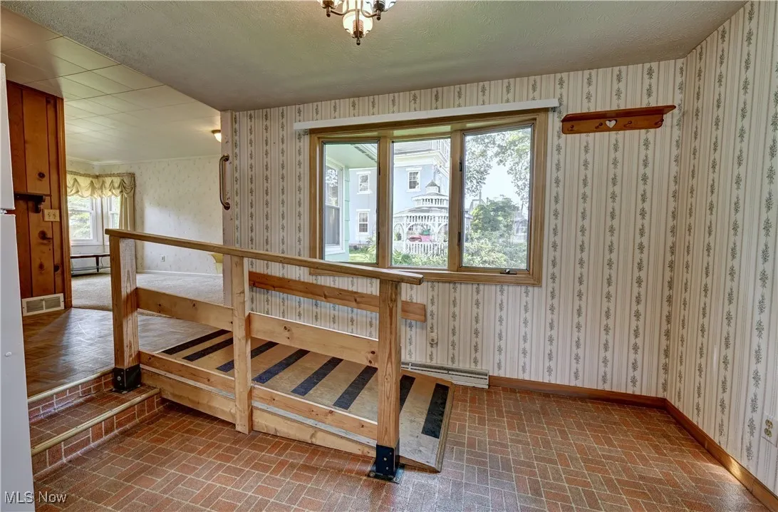 Dining room featuring brick patterned flooring and wallpapered walls