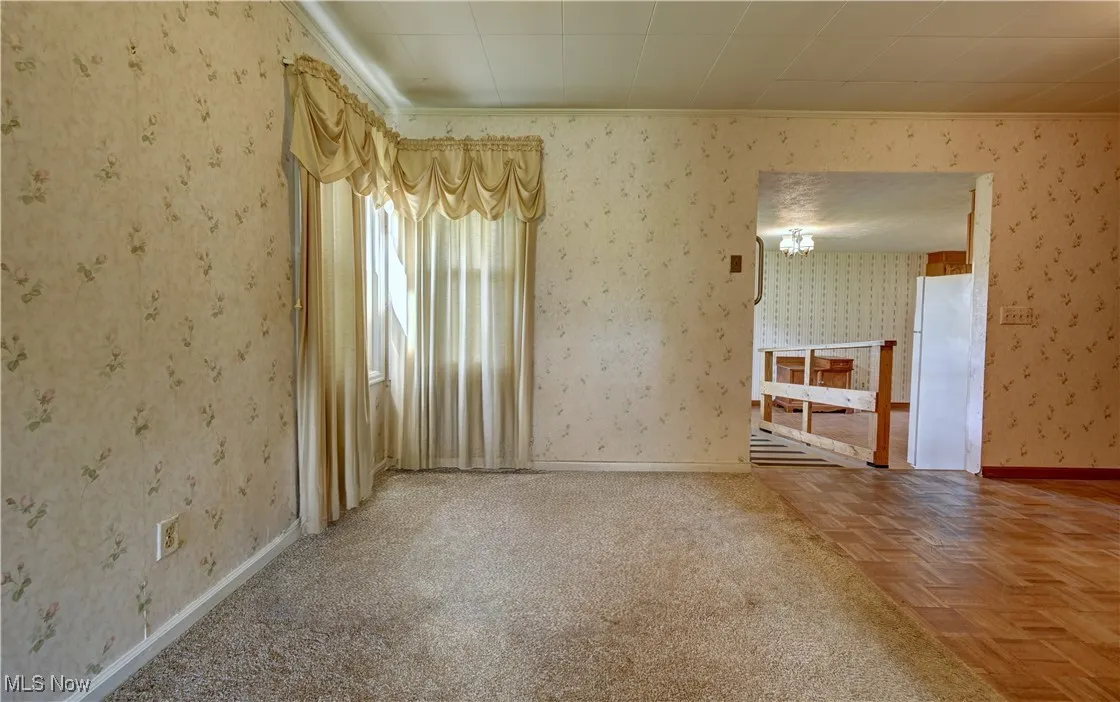 Spare room featuring wallpapered walls and ornamental molding