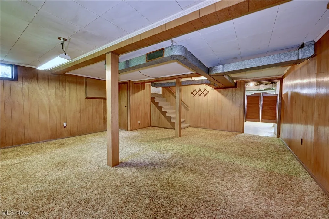 Below grade area with wood walls, carpet floors, and stairway