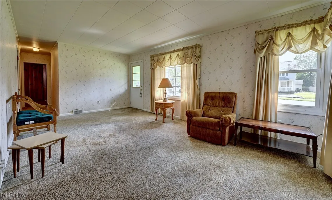 Living area featuring wallpapered walls and carpet