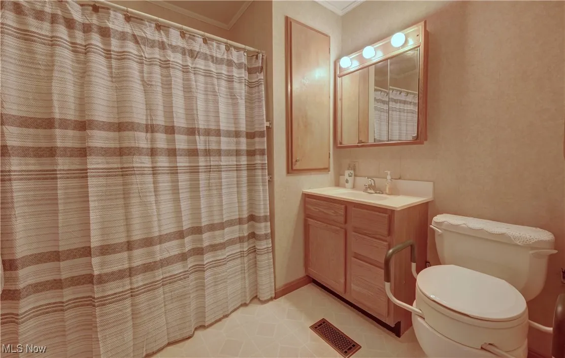Full bath with ornamental molding, vanity, curtained shower, and tile patterned flooring