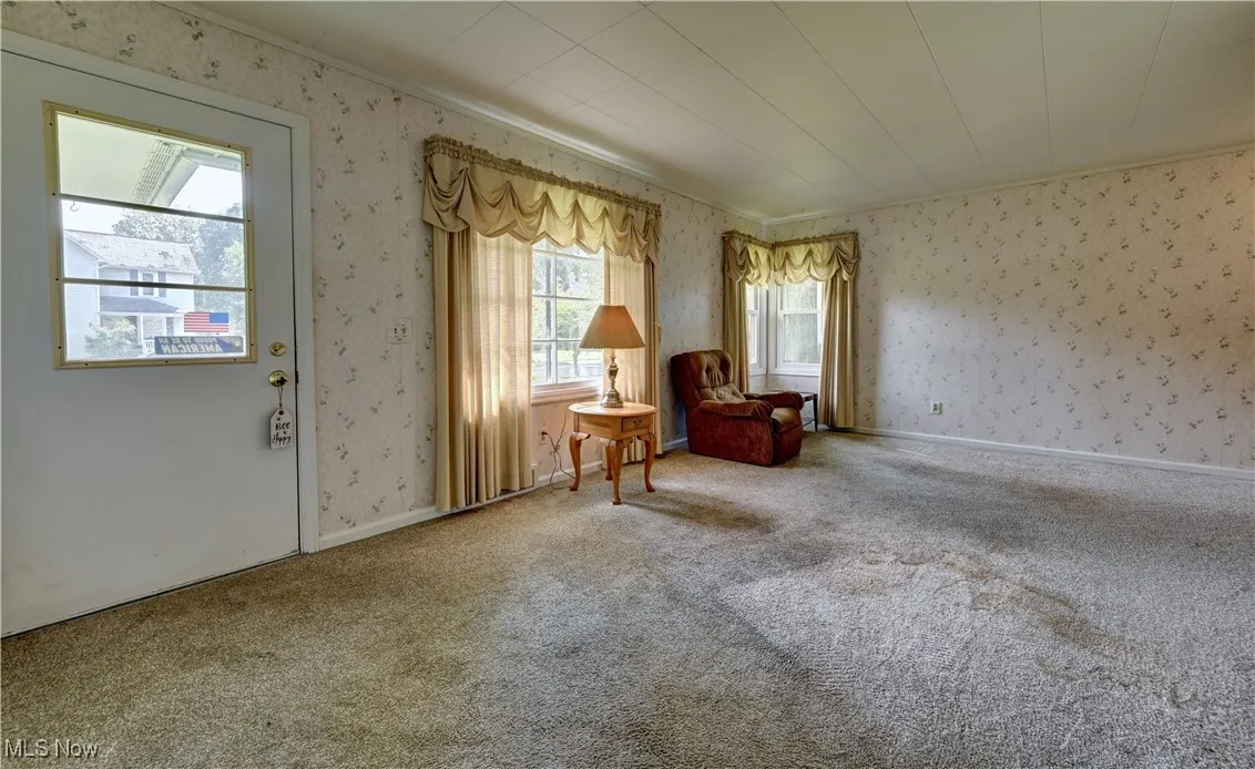 Living area featuring wallpapered walls and carpet