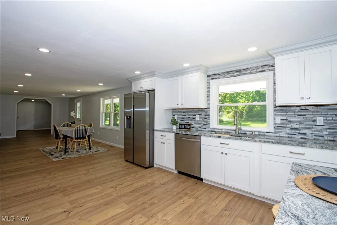 Kitchen featuring stainless steel appliances, tasteful backsplash, white cabinetry, light stone countertops, and recessed lighting