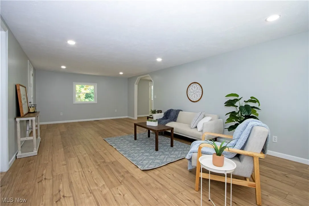 Living area with arched walkways, light wood-type flooring, and recessed lighting