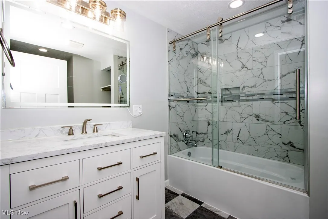 Bathroom featuring bath / shower combo with glass door, vanity, recessed lighting, and marble finish flooring