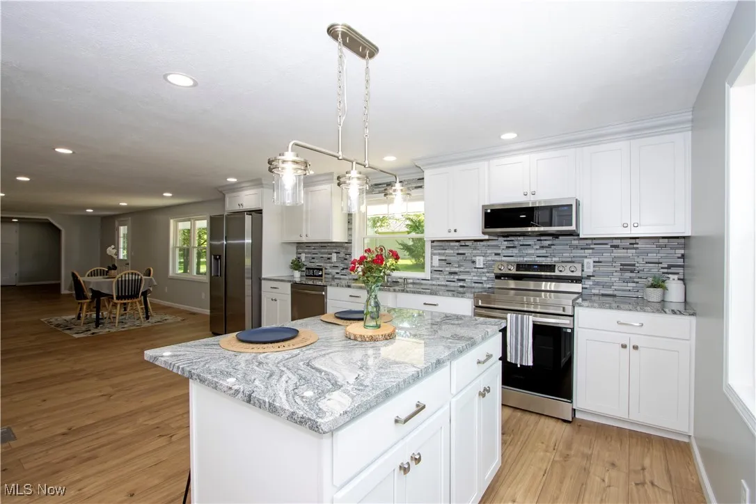 Kitchen with stainless steel appliances, light wood-type flooring, recessed lighting, decorative backsplash, and white cabinetry