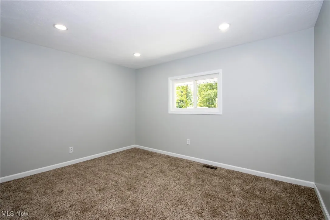 Carpeted spare room with baseboards and recessed lighting