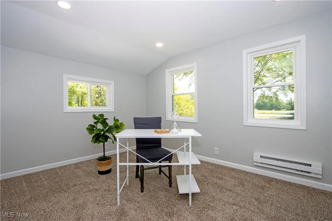 Carpeted office space featuring a baseboard radiator, vaulted ceiling, healthy amount of natural light, and recessed lighting