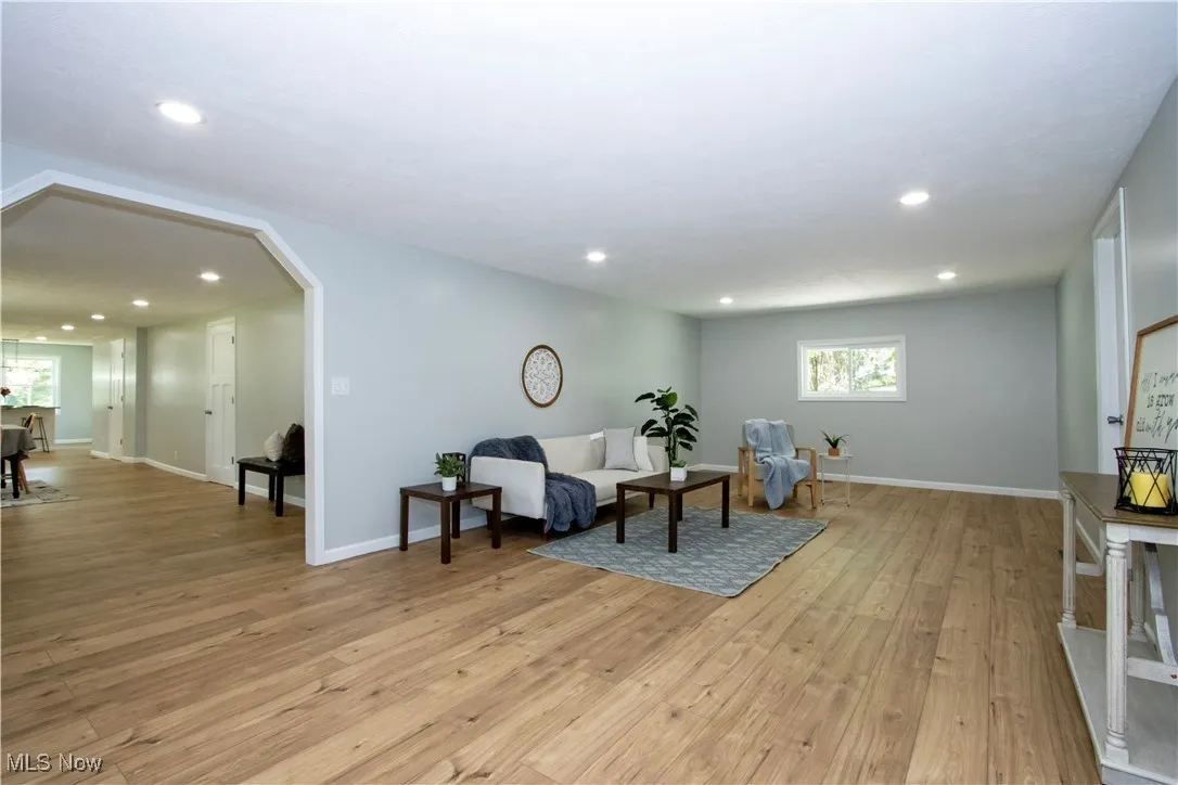 Living area featuring arched walkways, light wood finished floors, and recessed lighting