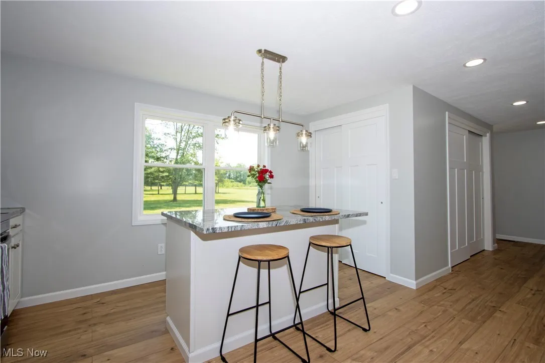 Kitchen featuring recessed lighting, light wood-style flooring, a kitchen bar, a kitchen island, and decorative light fixtures